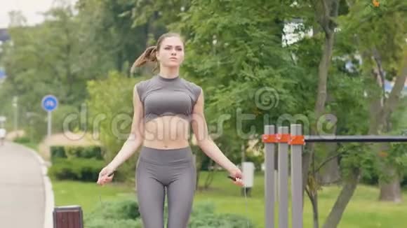 健身妇女在夏季公园用跳绳在户外训练视频的预览图