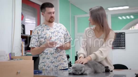 兽医为猫开药和一个女人谈论猫的健康室内兽医诊所视频的预览图