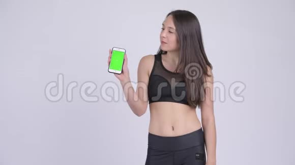 年轻快乐的女人带着手机竖起大拇指准备去健身房视频的预览图