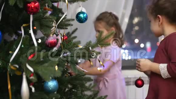 两个小女孩把圣诞玩具挂在圣诞树上为圣诞老人装饰圣诞树视频的预览图