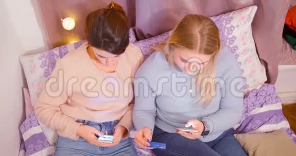两位快乐的年轻女性在网上购买使用笔记本电脑手机上的购物应用程序进行购买视频的预览图
