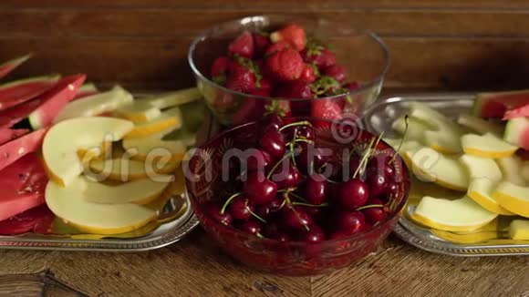 新鲜夏季水果樱桃有机草莓瓜片老式水晶碗中的西瓜放在旧木桌上视频的预览图