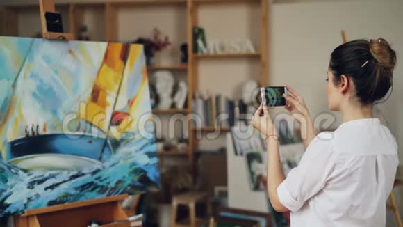女画家正在用现代智能手机拍摄她美丽的照片触摸屏幕视频的预览图