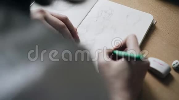 女孩在笔记本上画铅笔画从她肩膀上看到的视频的预览图