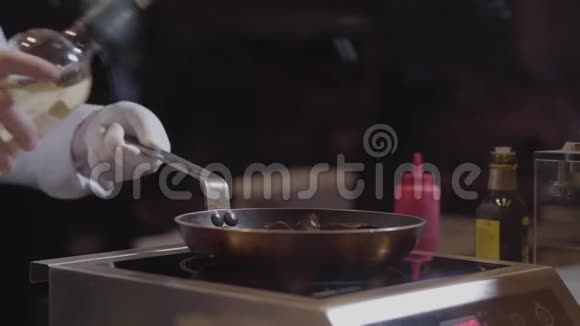 厨师手戴白色橡胶手套在煎锅中倒入白葡萄酒在现代餐厅烹饪美味的菜肴视频的预览图