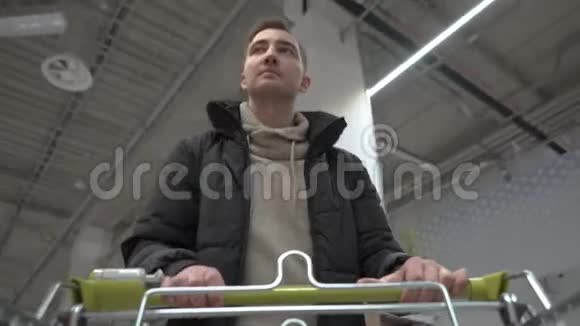 年轻漂亮的男人穿过超市购物车视图视频的预览图