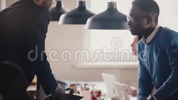 快乐非裔美国员工坐在办公室桌上与老板握手微笑玩球慢动作特写视频的预览图