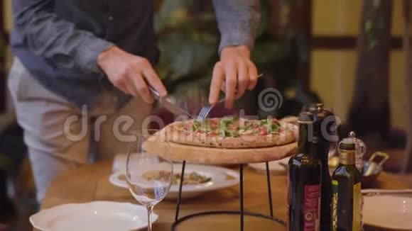 不认识的人用刀叉在餐馆的桌子上切美味的披萨精致的食物视频的预览图