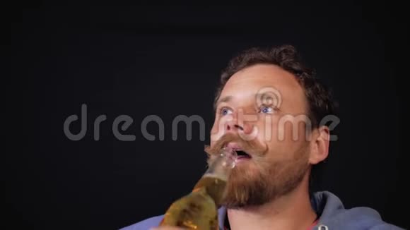 一个留着胡子和胡子的男人从瓶子里喝啤酒4k视频视频的预览图