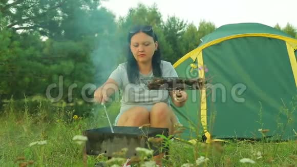帐篷附近的一位年轻女子在煤上炸肉喝茶视频的预览图