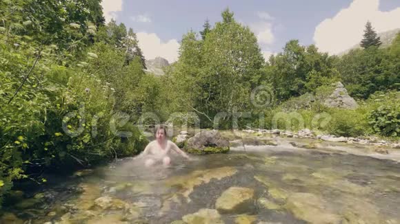 年轻人在河里洗澡摇湿头发慢动作视频的预览图