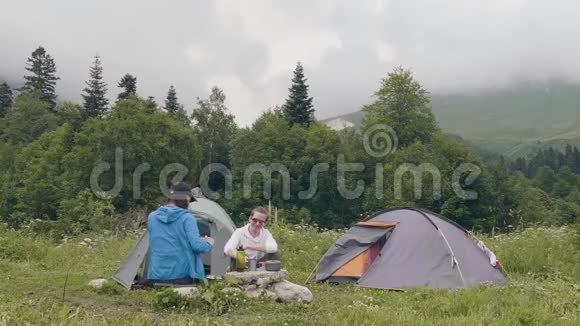 男人和女人在露营帐篷和山景背景下休息视频的预览图