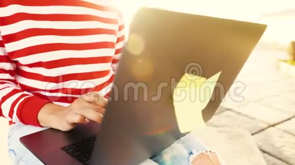 在户外对着夕阳使用笔记本电脑的女人视频的预览图