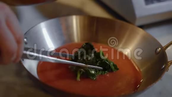 厨师把叶子和贻贝放在深铝锅里里面有红色酱汁的把手准备餐厅的海鲜视频的预览图