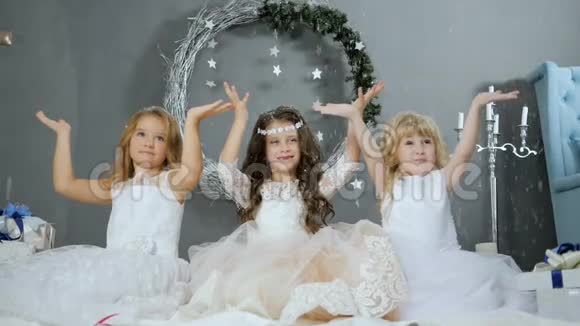 年的假期孩子们穿着白色连衣裙举起双手在工作室里捕捉人造雪视频的预览图