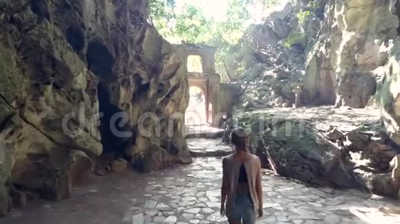 后面的女孩从石拱门穿过洞穴视频的预览图