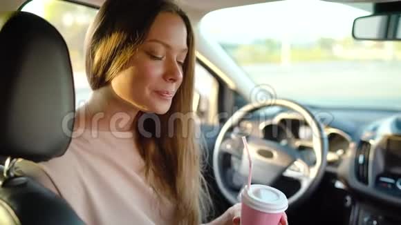 美丽开朗的女孩坐在车里喝着咖啡笑着视频的预览图