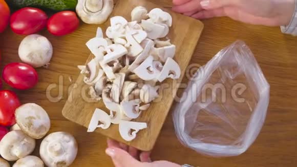 女人手把蘑菇放进厨房桌子上的袋子里视频的预览图