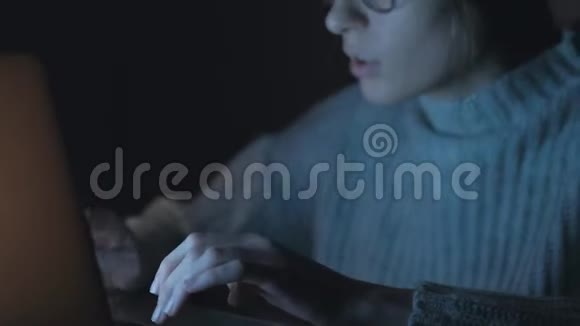 向上倾斜女性自由职业者晚上在笔记本上工作视频的预览图