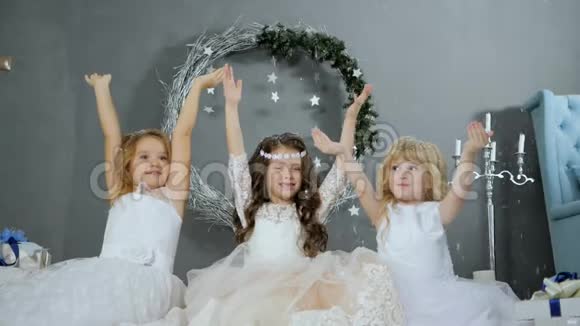 圣诞节前夕小女孩举起双手在新年装饰的背景下在工作室里人工雪视频的预览图