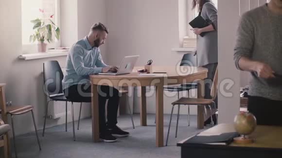 年轻的女老板穿着正式的衣服坐下来由男性员工用笔记本电脑帮助现代办公室视频的预览图