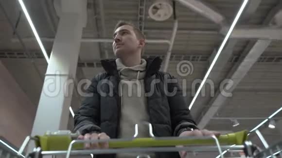 年轻漂亮的男人穿过超市购物车视图视频的预览图