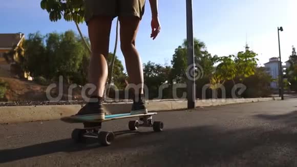 慢动作女孩在公园里用棕榈树骑滑板视频的预览图