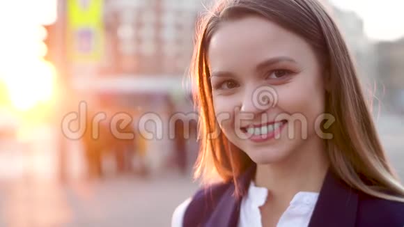 年轻迷人的女孩在傍晚的城市风景中微笑着看着镜头视频的预览图