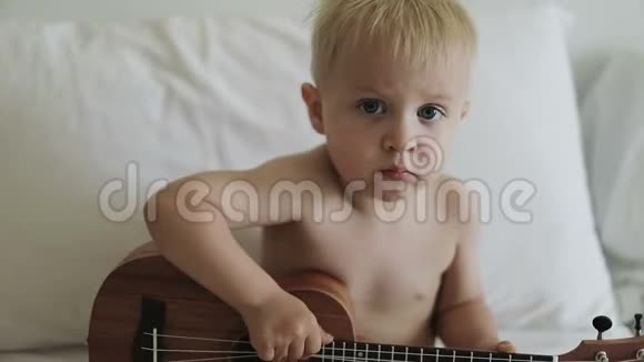 可爱的金发孩子玩四弦琴视频的预览图