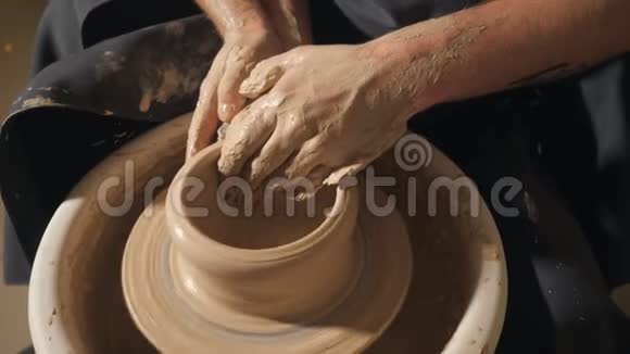 两只交织在一起的手在陶工的轮子上形成一盆粘土视频的预览图