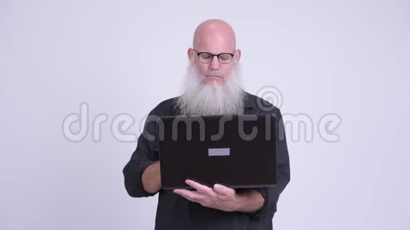成熟的秃头男人用笔记本电脑看上去很震惊视频的预览图