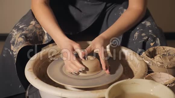 这个女孩在陶工的轮子上做了一壶粘土双手特写视频的预览图