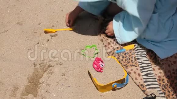一个穿浴袍的孩子在海滩上玩玩具视频的预览图