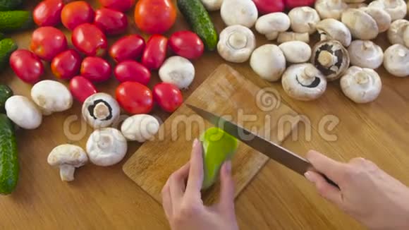 女人手在厨房桌子上的木板上用蔬菜剥青椒视频的预览图