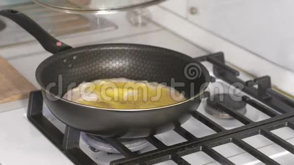 人的手在煤气炉上的煎锅里合上用香肠准备炒鸡蛋的盖子视频的预览图