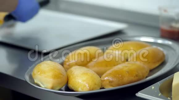 厨师和厨师手戴手套把刚煮熟的馅饼放在一个托盘上供出售视频的预览图