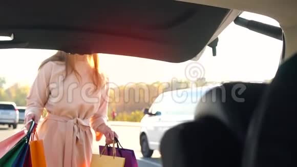漂亮女孩把购物袋放在汽车后备箱里打算开车离开慢动作视频的预览图