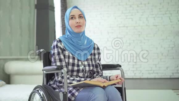 一个戴着头巾的漂亮年轻女人是盲目的或虚弱的一个轮椅在读盲文字体视频的预览图