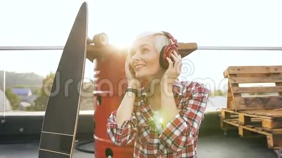 可爱的金发女孩戴着红色耳机听音乐和跳舞带着耳机跳舞的年轻时髦女人微笑着视频的预览图