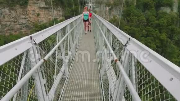两个快乐的年轻白种人妇女走在铰链桥上的山河与3DOCulus视频的预览图