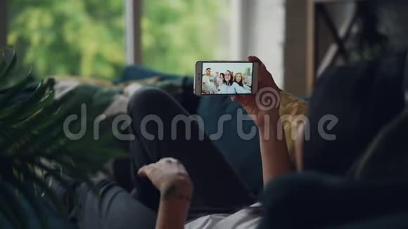 深色头发的后视图制作在线视频电话手持智能手机看屏幕说话在室内打手势视频的预览图