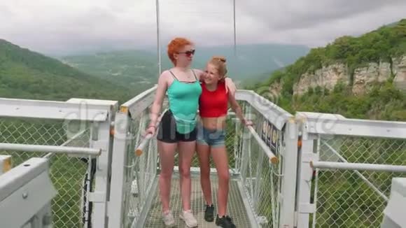 两个白种人姐妹在高山上的吊桥上笑着拥抱着视频的预览图