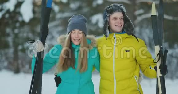 年轻夫妇载着滑雪板在美丽的冬林中聊天复制空间的侧视图视频的预览图