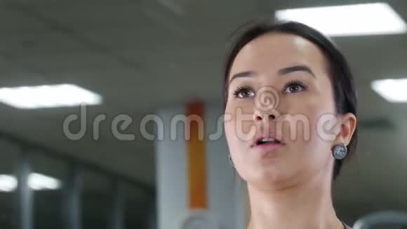 一个年轻的女人用哑铃抽她的手肌肉照镜子肖像视频的预览图