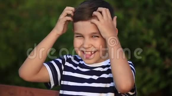 一个穿条纹T恤的小男孩在微笑和欢呼春天晴朗的天气视频的预览图