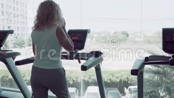 在健身房做跑步机和打电话的老女人视频的预览图