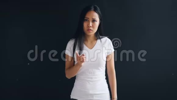 愤怒的亚洲女孩在黑色背景下大喊大叫和打手势表达负面情绪的肖像视频的预览图