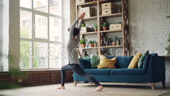女瑜伽教练独自在家练习做站立在地板上和移动身体的体式健康视频的预览图
