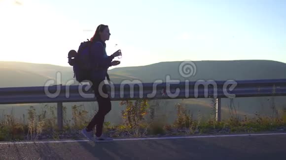 女游客背着背包在山里的路上散步喝着水视频的预览图
