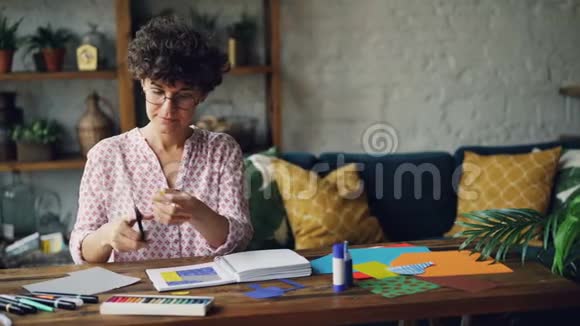 年轻的黑发女孩在设计插图切割溅纸然后在笔记本上粘贴数字使用视频的预览图